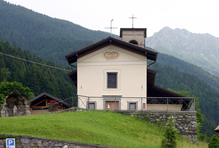 CHIESA DI SANT'ANNA IN PALINE - Sul lato destro della statale Borno-Dezzo, giusto all'ingresso del minuscolo agglomerato urbano di Paline, frazione di Borno, si erge, sopra un promontorio naturale, un modesto santuario seicentesco. Anticamente era consacrato alla SS. Trinità, mentre attualmente onora la figura di S. Anna, santo patrono della frazione. L'impianto architettonico come abbiamo già accennato è del seicento; le facciate molto semplici non presentano lesene nè cornicioni. Il portale d'ingresso è architravato e le finestre hanno cornici lisce. L'interno, costituito da due campate, presenta lesene che dividono la navata dal coro. Sulla volta vi sono impressi affreschi di recente fattura raffiguranti S. Anna con Maria bambina, la presentazione di Gesù al tempio e la Trinità con la colomba. Si ha notizie di opere restaurative avvenute negli anni 1939 e 1957. (Da 